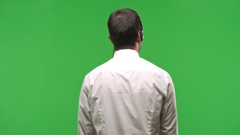 Handsome telemarketer man on back position looking back while scratching head on green screen chroma key