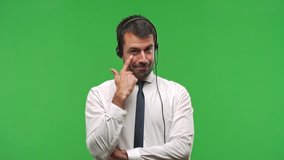 Handsome telemarketer man standing and looking to the front opening the eye with finger on green screen chroma key