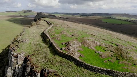 Aerial-Flying over ancient Roman wall (Hadrian's Wall) along the Scottish border-Unidentifiable hiker walks along the wall with a dog