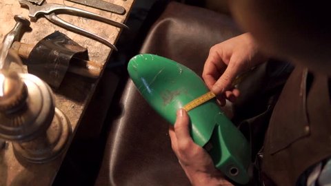 Shoemaker measuring a shoe with measure tape in workshop
