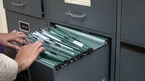 Employees search for documents in a filing cabinet at the office.