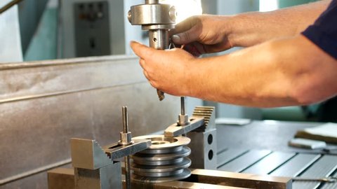 The man specialist checks the measuring tool with the size of drilling a metal pulley and inserts a drill into a drilling machine, individual entrepreneur