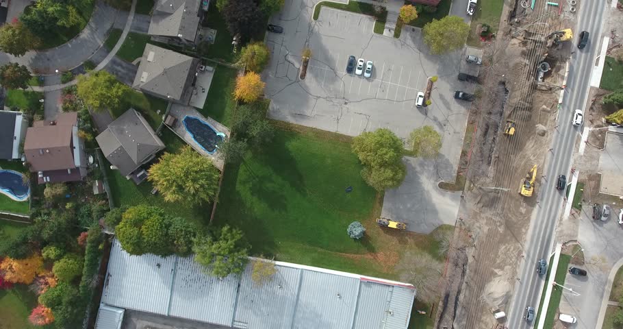 Descending Into Empty Green Space Near Parking Lot Construction And Houses Ae
