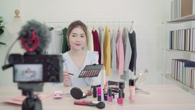 Beauty blogger present beauty cosmetics sitting in front camera for recording video. Beautiful asian woman use cosmetics while review make up tutorial broadcast live video to social network 