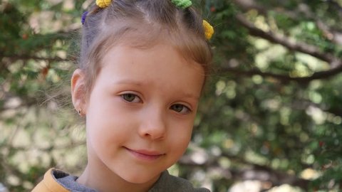 Cute little child girl face portrait in a park outdoors