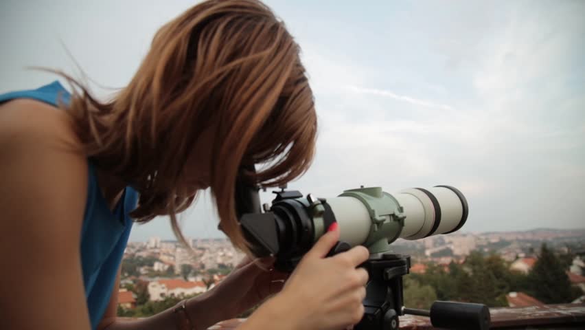 Young woman looking at the sky with astronomical telescope.