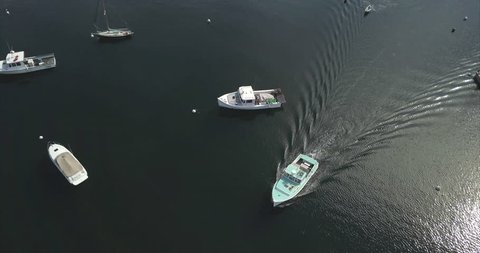 Rockport, Maine / United States - 09 22 2017: ROCKPORT, MAINE, SEPTEMBER 2017 - A blue motor boat and a rowboat passing through Rockport Harbor.