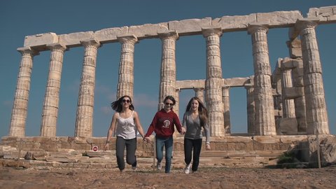 Cape Sounion, Greece - 03 04 2017: Cape Sounion, Greece, March 2017, Three girls jumping in slow motion at Cape Sounion temple in Greece.