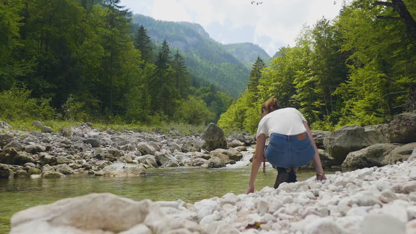 Salzburgerland Austria, young woman checking water of mountain river slow motion