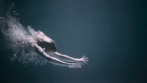 Beautiful woman swimming underwater in white elegant dress