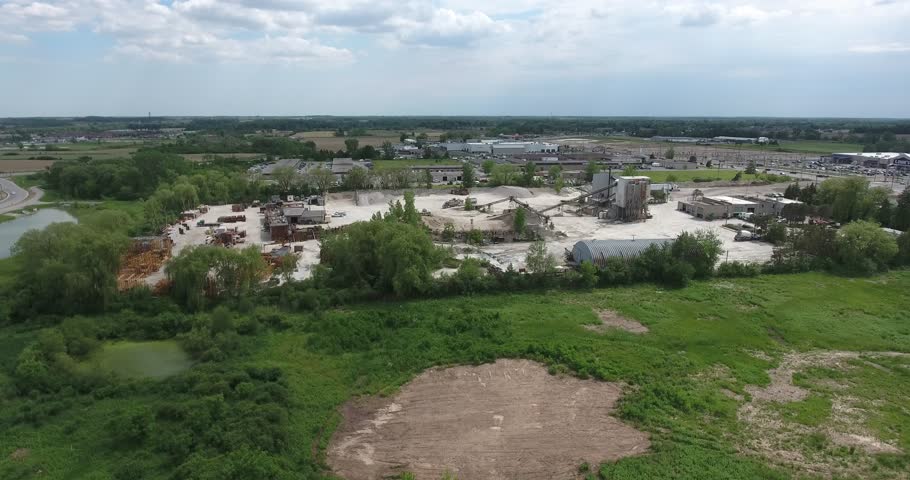 Constuction Company In Distance Aerial Flying Down Towards Grassy Field