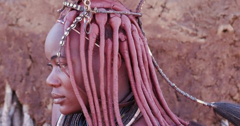 4K close-up tilt up view of a pretty Himba girl showing head gear and neck jewellery,Namibia