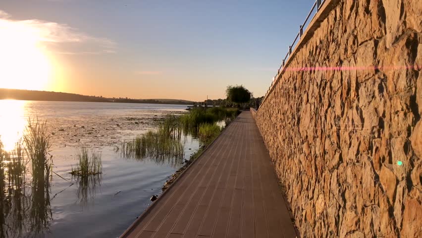Young girl walking near the lake in sunset