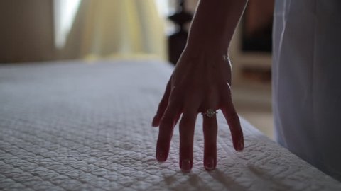 Close up of hand caressing bed towards dress