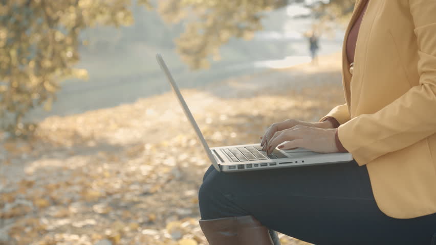 Girl working on a laptop in the park Sunny autumn day in the park. 