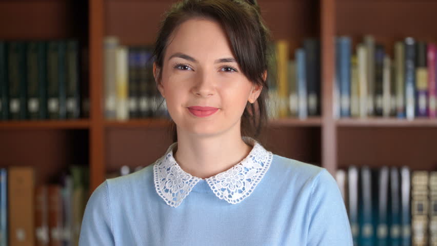 Footage portrait of smiling beautiful pretty woman and doing thumb up in library office bookshelf background. 4k video