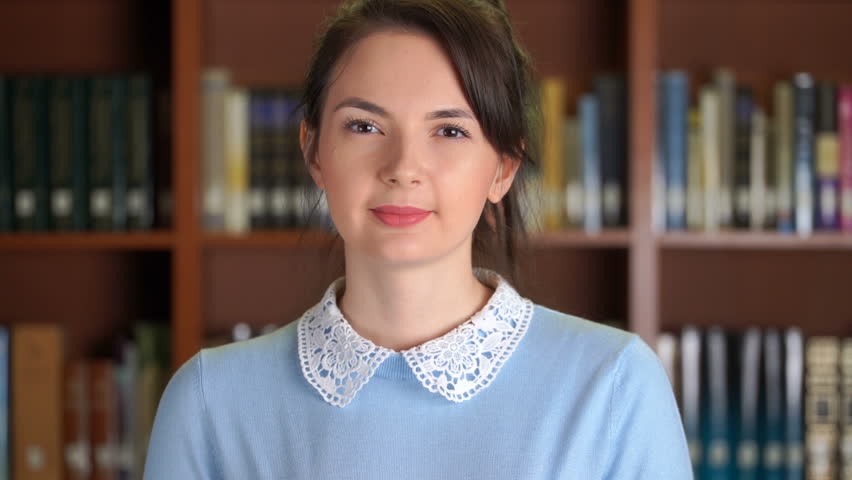 Footage portrait of smiling beautiful pretty woman in library office bookshelf background. 4k video