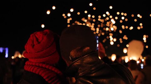 Romantic scene of a couple watching floating lanterns. Thousands of lanterns fill the night sky creating a beautiful and cute love scene.