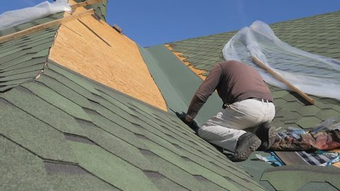 soft roof of shingles. Repair of the roof of a residential house. installation of soft tiles. partial replacement of the damaged roof. Dot repair. carpenter throws a hammer up and catches it. Worker