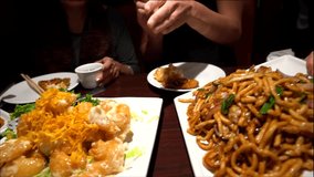 This close up video shows a feast of delicious dishes and rice bowls being served to a group of people at a Chinese restaurant.