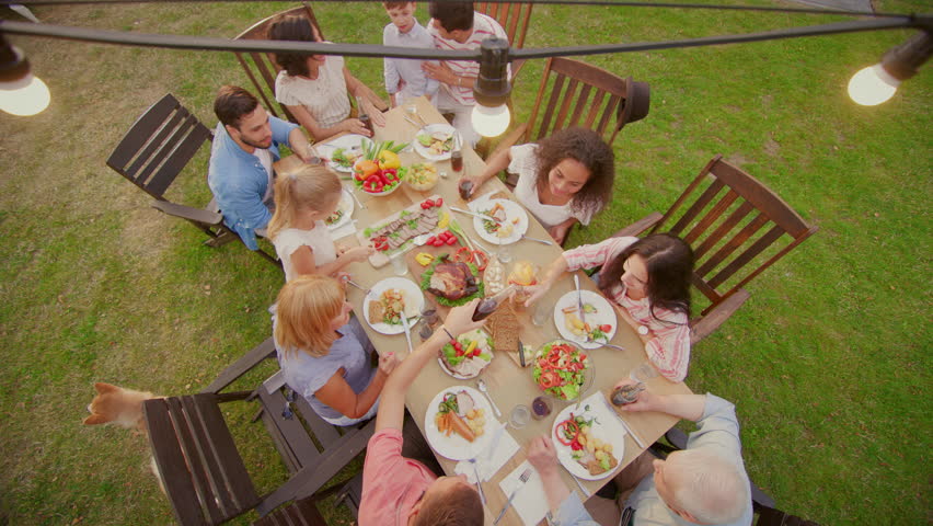 Big Family Garden Party Celebration, Gathered Together at the Table Relatives and Friends, Young and Elderly are Eating, Drinking, Passing Dishes, Joking and Having Fun. Top Down Camera Shot. Royalty-Free Stock Footage #1018050763