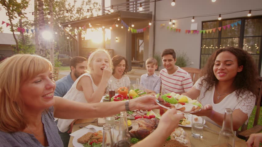 Big Family Garden Party Celebration, Gathered Together at the Table Relatives and Friends, Young and Elderly are Eating, Drinking, Passing Dishes, Joking and Having Fun. Royalty-Free Stock Footage #1018050772