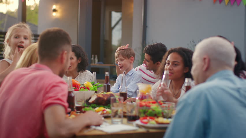 Big Family Garden Party Celebration, Gathered Together at the Table Relatives and Friends, Young and Elderly are Eating, Drinking, Passing Dishes, Joking and Having Fun. Royalty-Free Stock Footage #1018050775