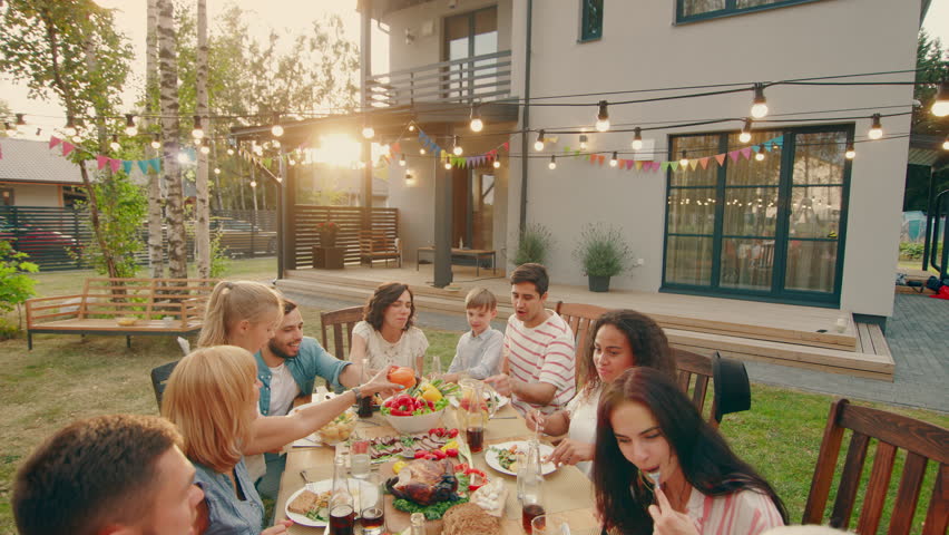 Big Family Garden Party Celebration, Gathered Together at the Table Relatives and Friends, Young and Elderly are Eating, Drinking, Passing Dishes, Joking and Having Fun. Top Down Camera Shot. Royalty-Free Stock Footage #1018050826