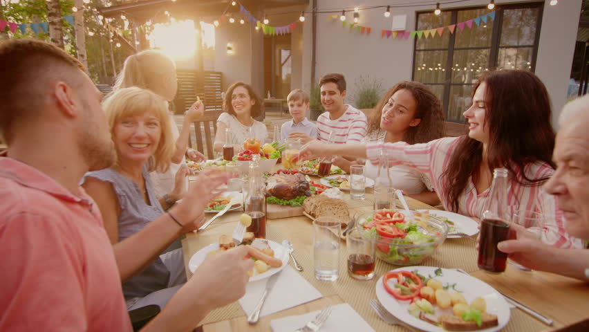 Big Family Garden Party Celebration, Gathered Together at the Table Relatives and Friends, Young and Elderly are Eating, Drinking, Passing Dishes, Joking and Having Fun. | Shutterstock HD Video #1018052485