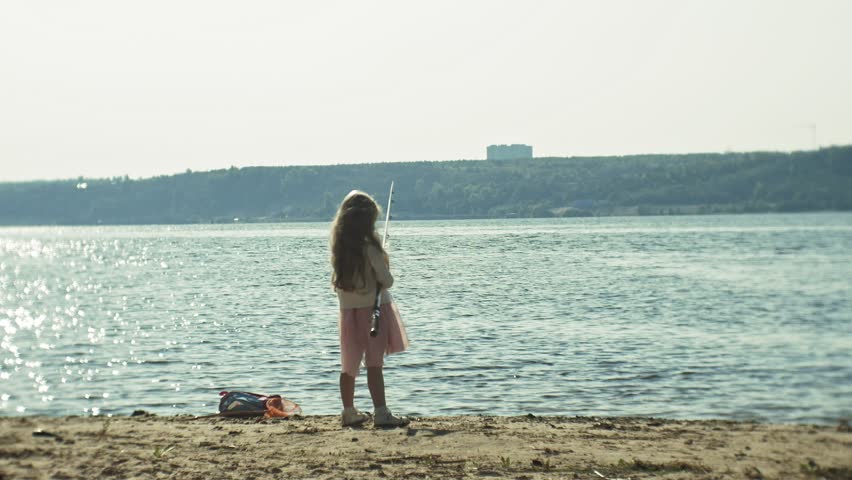 Cute little girl is playing with a fishing rod on a fishing boat near the river 4k