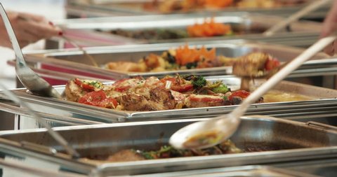 People group catering buffet food indoor in luxury restaurant with meat colorful fruits and vegetables. Close up. Banquet, lunch, bad nutrition, gluttony concept
