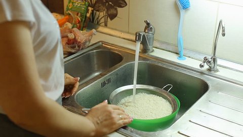 housewife washes rice in the kitchen for cooking pilaf at home