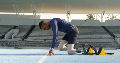 Side view of a disabled mixed-race athletic African american  getting ready for the race on a running track