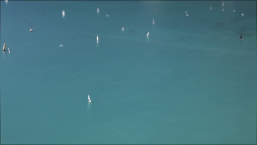 Beautiful tilt-shift miniature scene of a ships and sailing boats in a turqoise lake on a bright summer sunny day