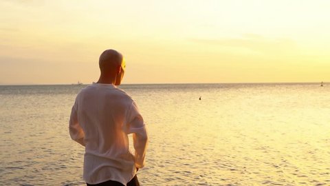 Man practicing Qigong at sunset by the sea