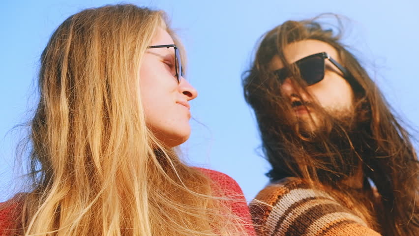 Young couple in sun glasses hugging and kissing in sunrise