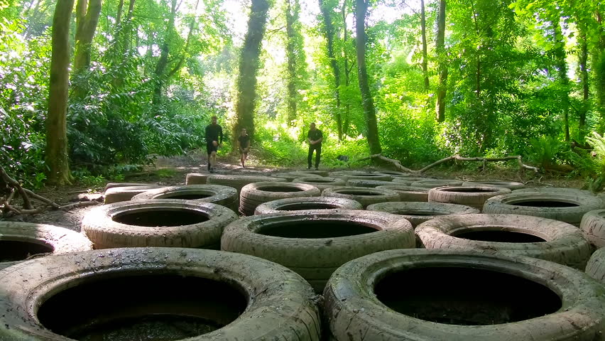Front view of fit Caucasian men training over tyres obstacle course at boot camp  - Powered by Shutterstock - Get 15% off with code: PIKWIZARD15