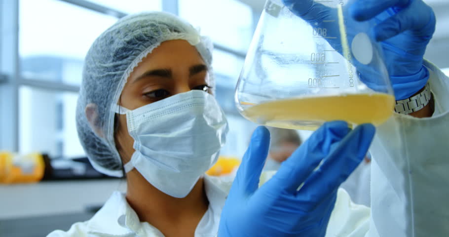 Front view of Caucasian female scientist looking at conical flask in laboratory,  Testing for Coronavirus Covid19 vaccine | Shutterstock HD Video #1018075921