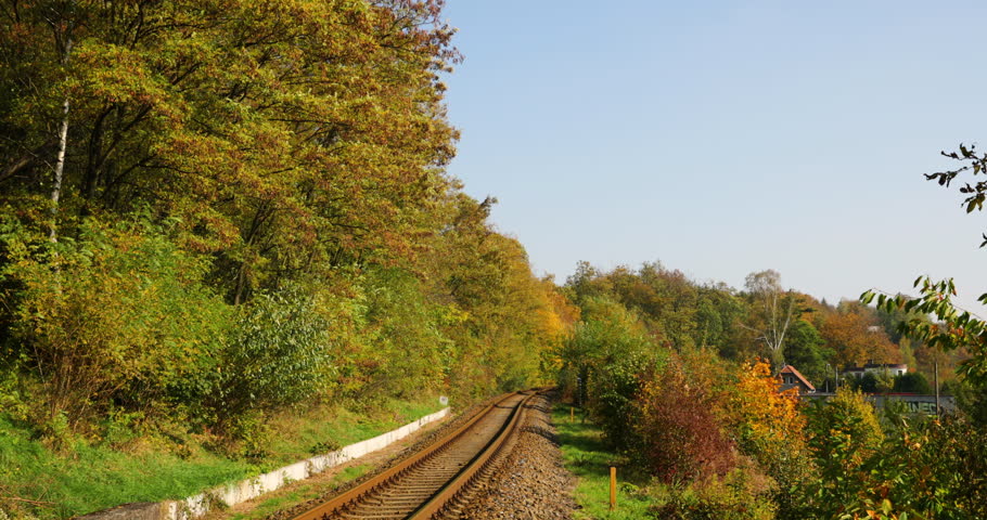 The transition between the railroad line from the right to the left during the sunny autumn day in slow motion.