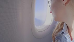 Attractive young girl looking out the window of an airplane