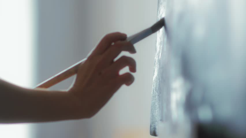 Close-up of the artist's hands holds a brush and paint on canvas oil