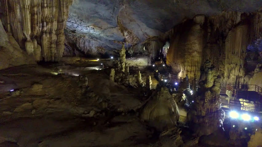 general view of magical stalactite and stalagmite structures of huge karst cavern hall visited by tourists