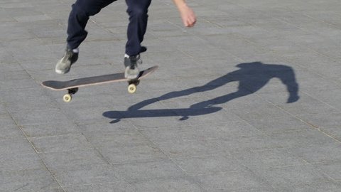 Unrecognizable Skater doing trick kickflip on flat, close-up view in slowmotion