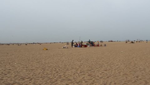 Chennai, Tamilnadu / India - 07 15 2018: Chennai India July 15 2018 handheld unedited footage of group of unidentified people sitting near sea shore at marina beach,having leisure time with sea breeze