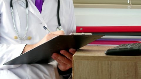 Male physician doctor writing rx prescription on clipboard for his patients. Close-up