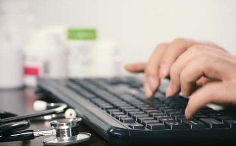 Close-up of a male doctor using a computer keyboard.