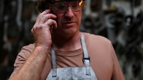 Close-up of blacksmith talking on mobile phone 