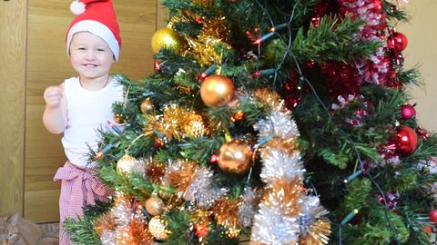 Infant baby christmas celebrate. Christmas baby costume, santa hat, christmas tree.