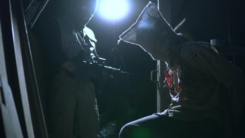 Terrified Hooded Hostage Held By Masked Armed Terrorists, Handcuffed To Chair. A Variety Of 4K Hostage Stories Available.