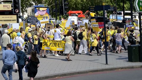 London, UK - June 22, 2018: High angle view on people holding up signs at Cystic Fibrosis protest in England to make Orkambi medicine drug free, yellow color clothes, marching, walking